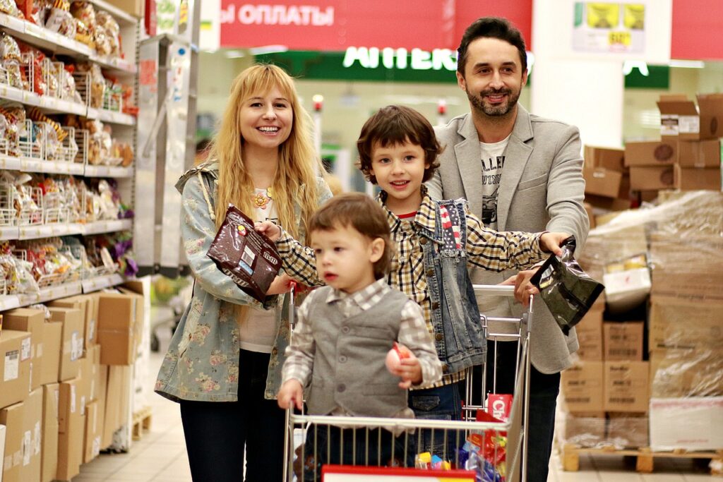 A family shopping in a grocery store. Two children are in the cart.